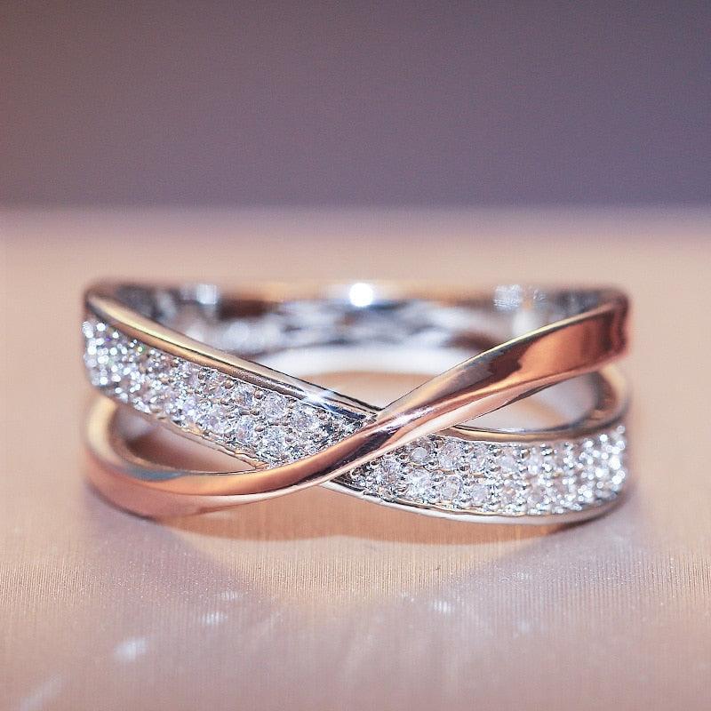 Anel feminino cruzado em prata com banho rosé e zircônias brilhantes cravejadas. Perfeito para mulheres que buscam um acessório luxuoso, moderno e cheio de charme para ocasiões especiais.