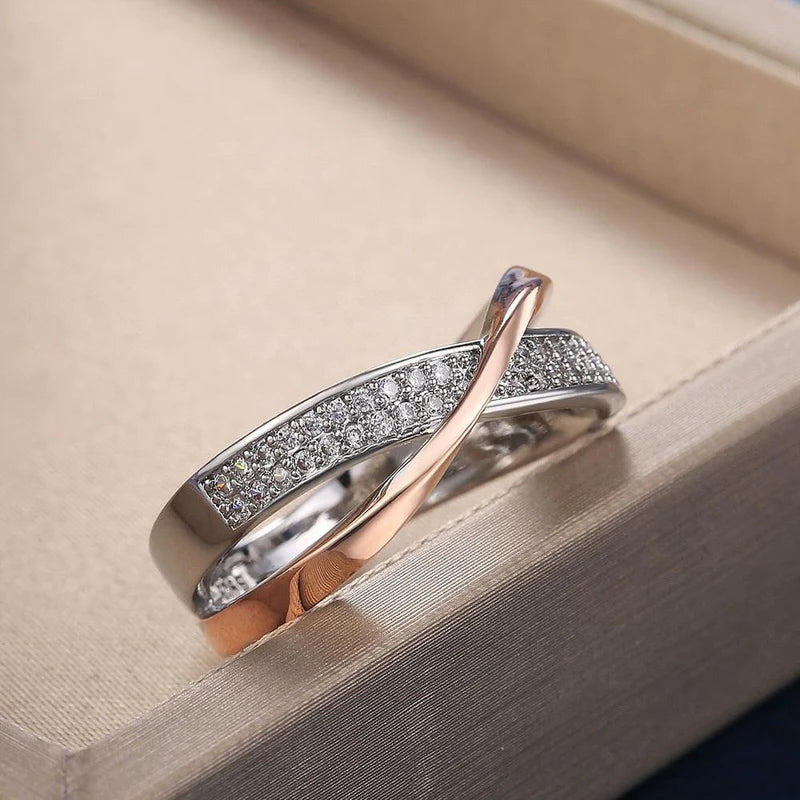 Anel feminino cruzado em prata com banho rosé e zircônias brilhantes cravejadas. Perfeito para mulheres que buscam um acessório luxuoso, moderno e cheio de charme para ocasiões especiais.