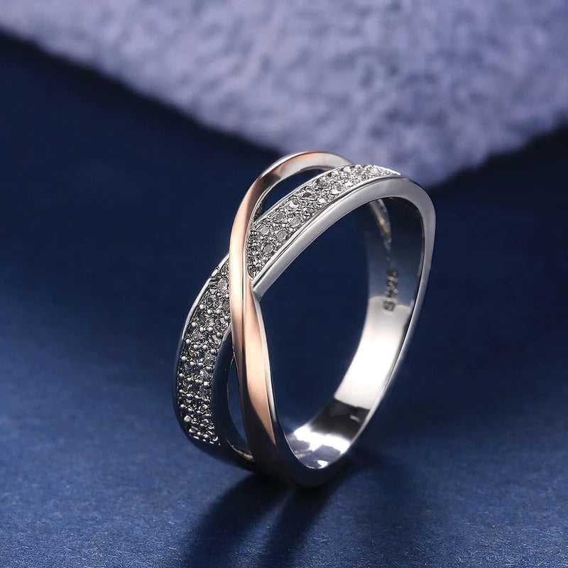 Anel feminino cruzado em prata com banho rosé e zircônias brilhantes cravejadas. Perfeito para mulheres que buscam um acessório luxuoso, moderno e cheio de charme para ocasiões especiais.