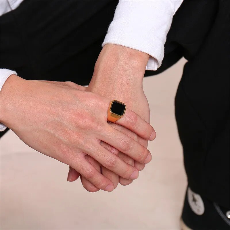 Anel masculino dourado com pedra ônix preta e acabamento polido. Ideal para compor looks elegantes com um toque de sofisticação e personalidade marcante.