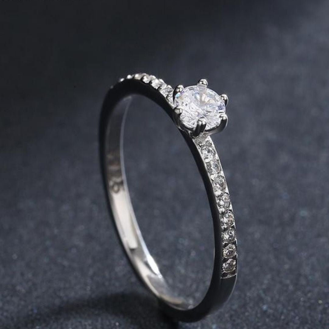Anel solitário feminino em prata com pedra central cravejada e detalhes delicados. Uma joia atemporal, perfeita para noivado ou para compor produções clássicas e românticas.