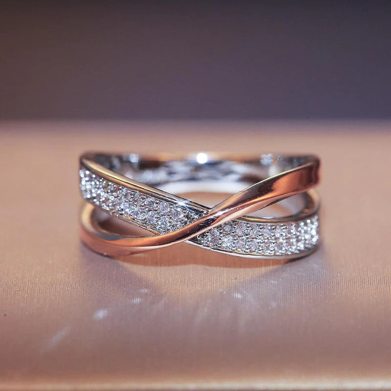 Anel feminino cruzado em prata com banho rosé e zircônias brilhantes cravejadas. Perfeito para mulheres que buscam um acessório luxuoso, moderno e cheio de charme para ocasiões especiais.